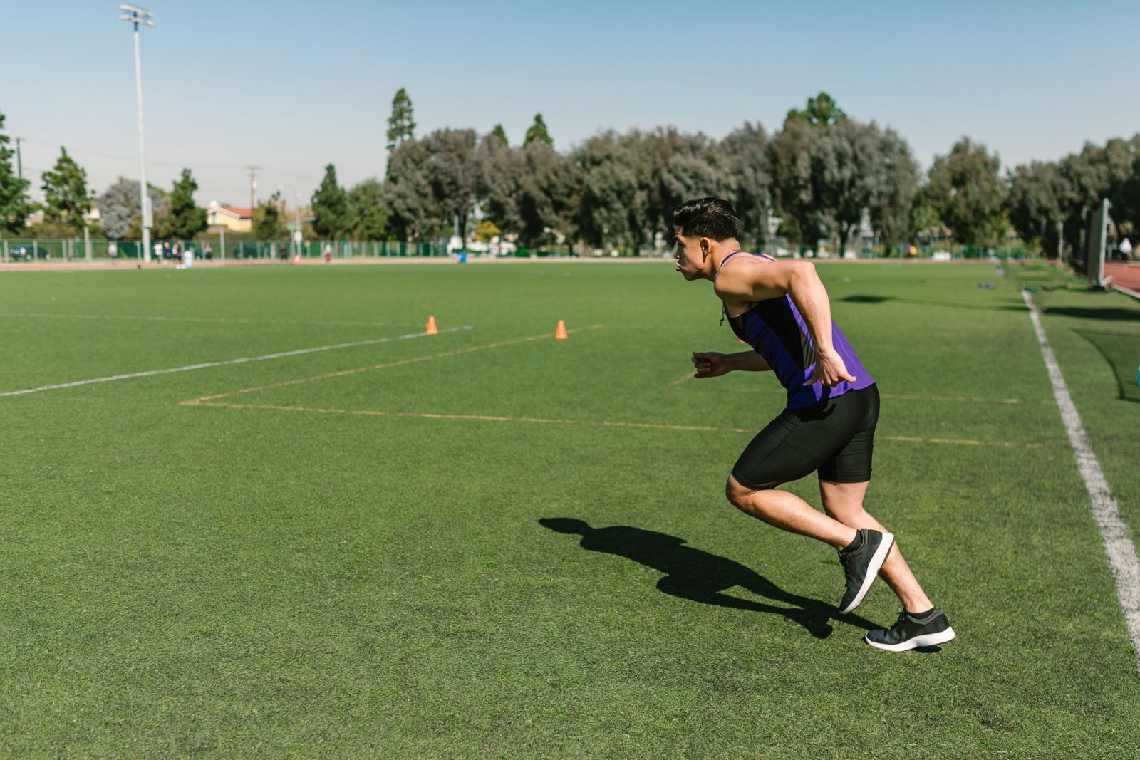 A runner pushing off into a sprint on a grass field