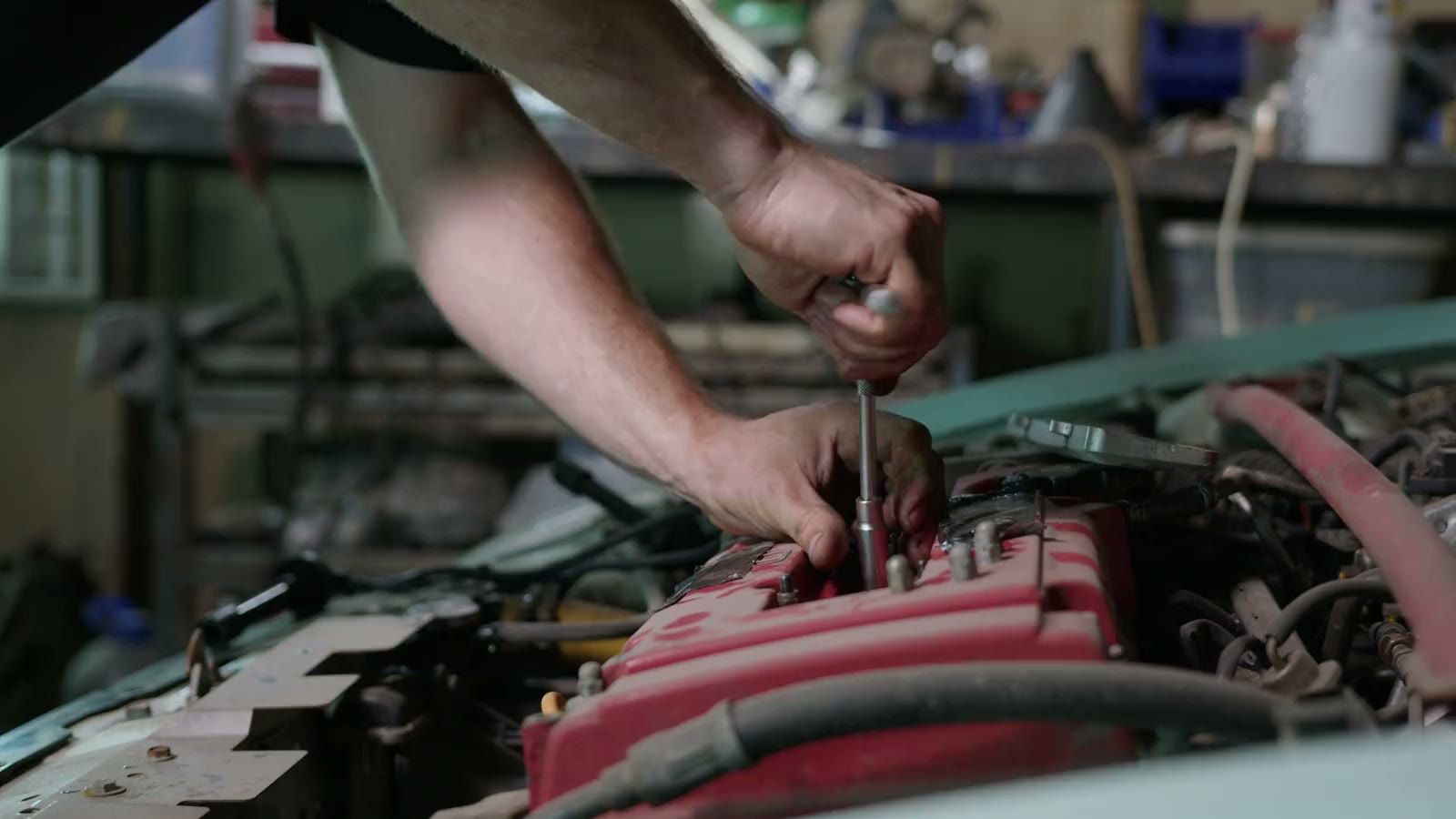 A mechanic's hands working on an engine with a socket wrench