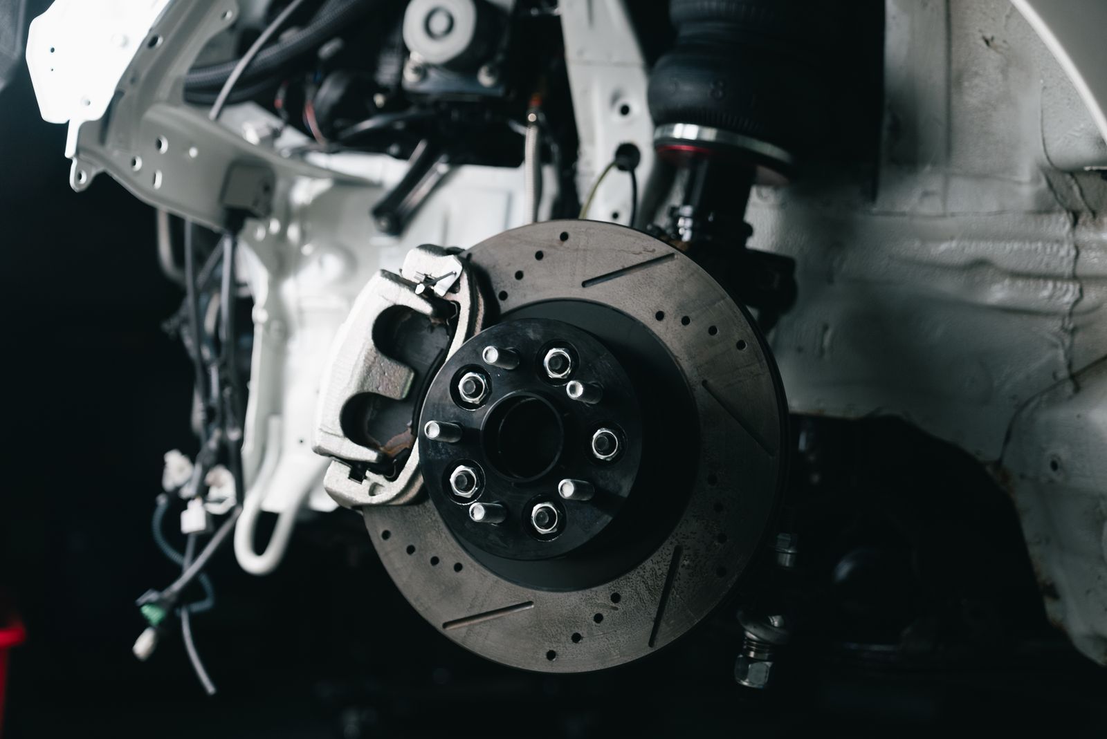 A large silver caliper over a slotted rotor on a white car