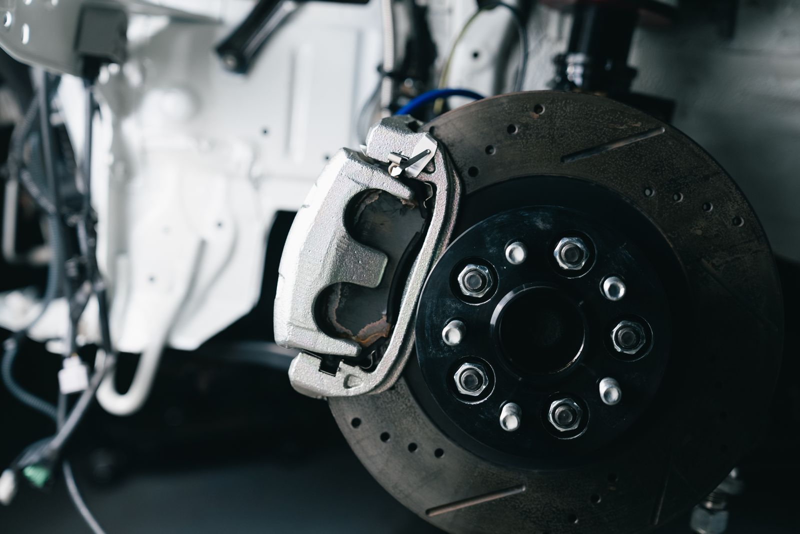 A drilled brake rotor and caliper in a clean bay