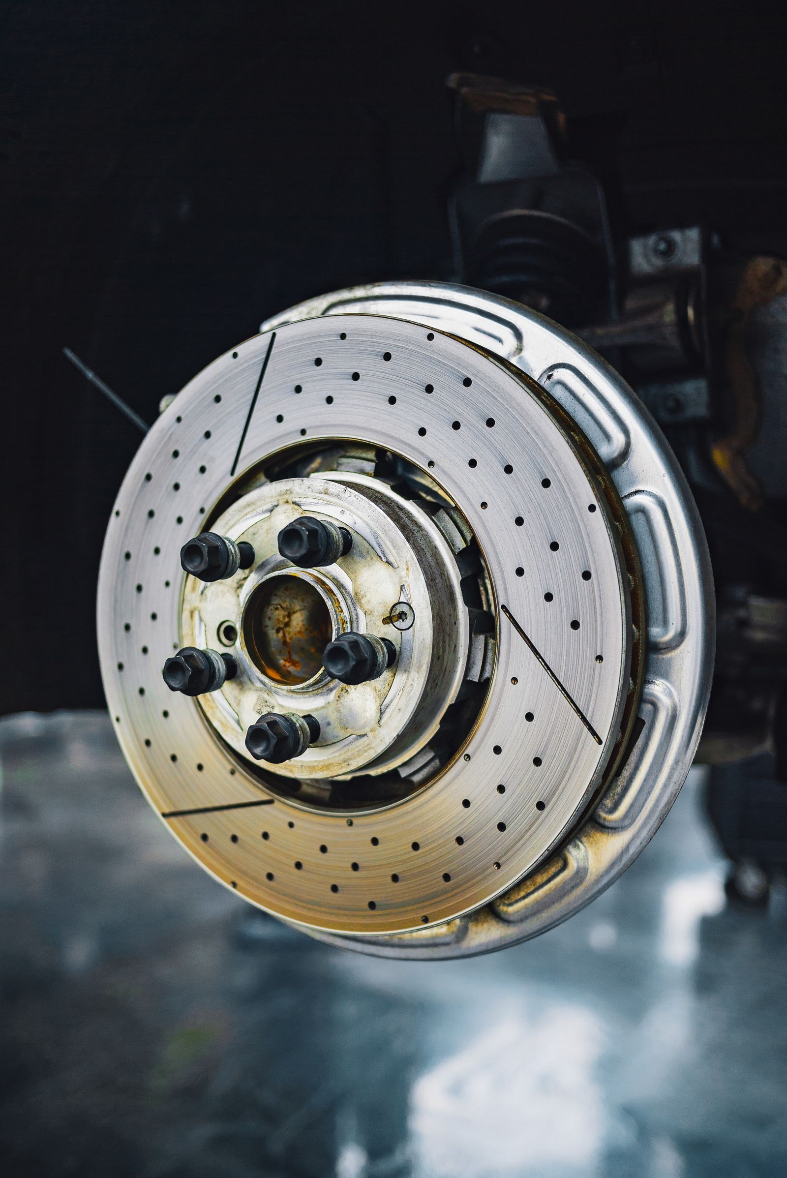 Close-up of a drilled brake rotor and hub on a car with its wheel off