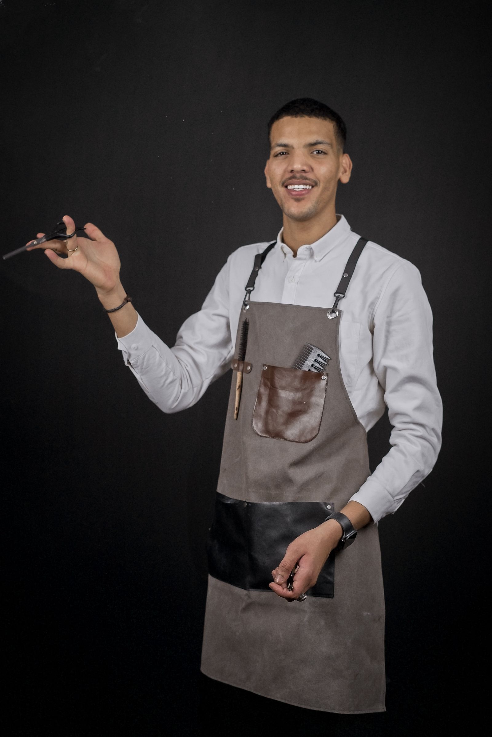 Tariq Hussain in a grey apron, holding scissors