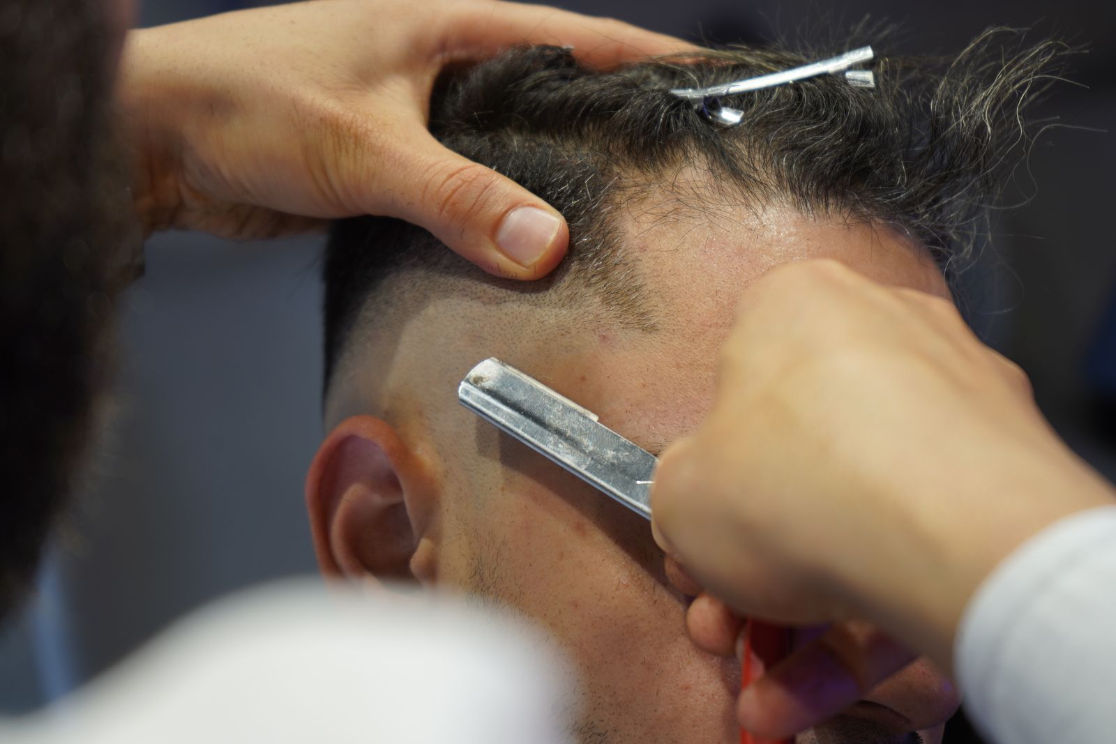 A straight razor cleaning up a part line on the side of a fade