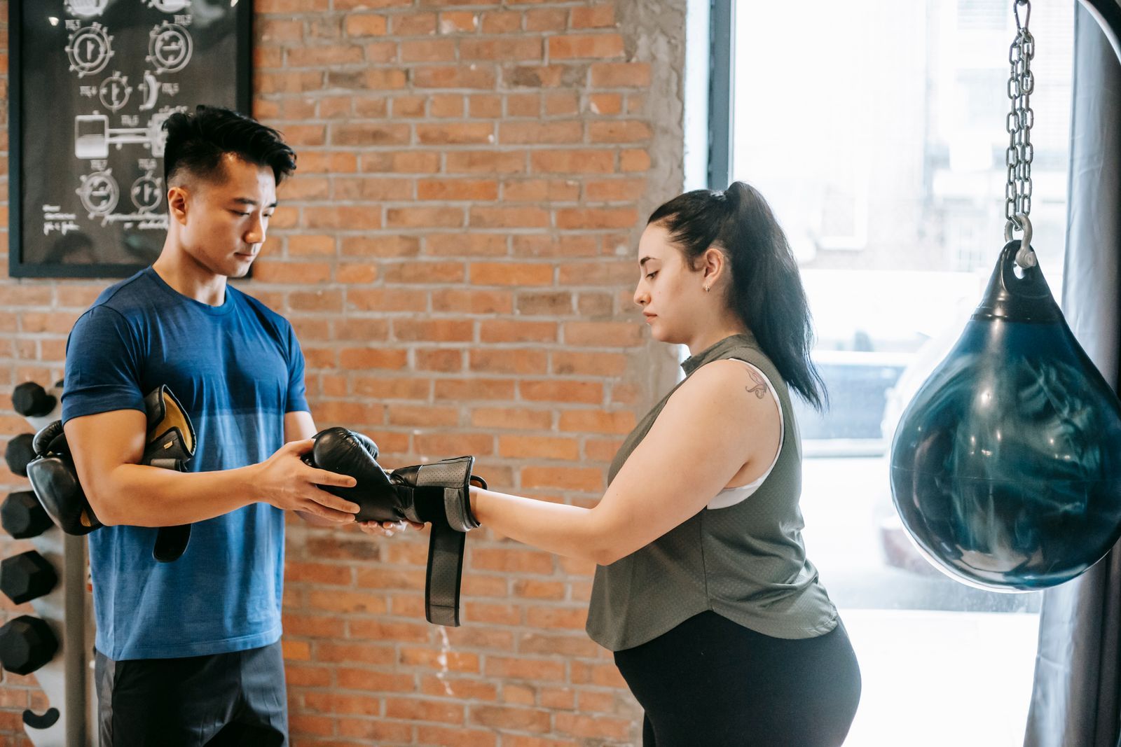 A coach helping a member fasten a boxing glove