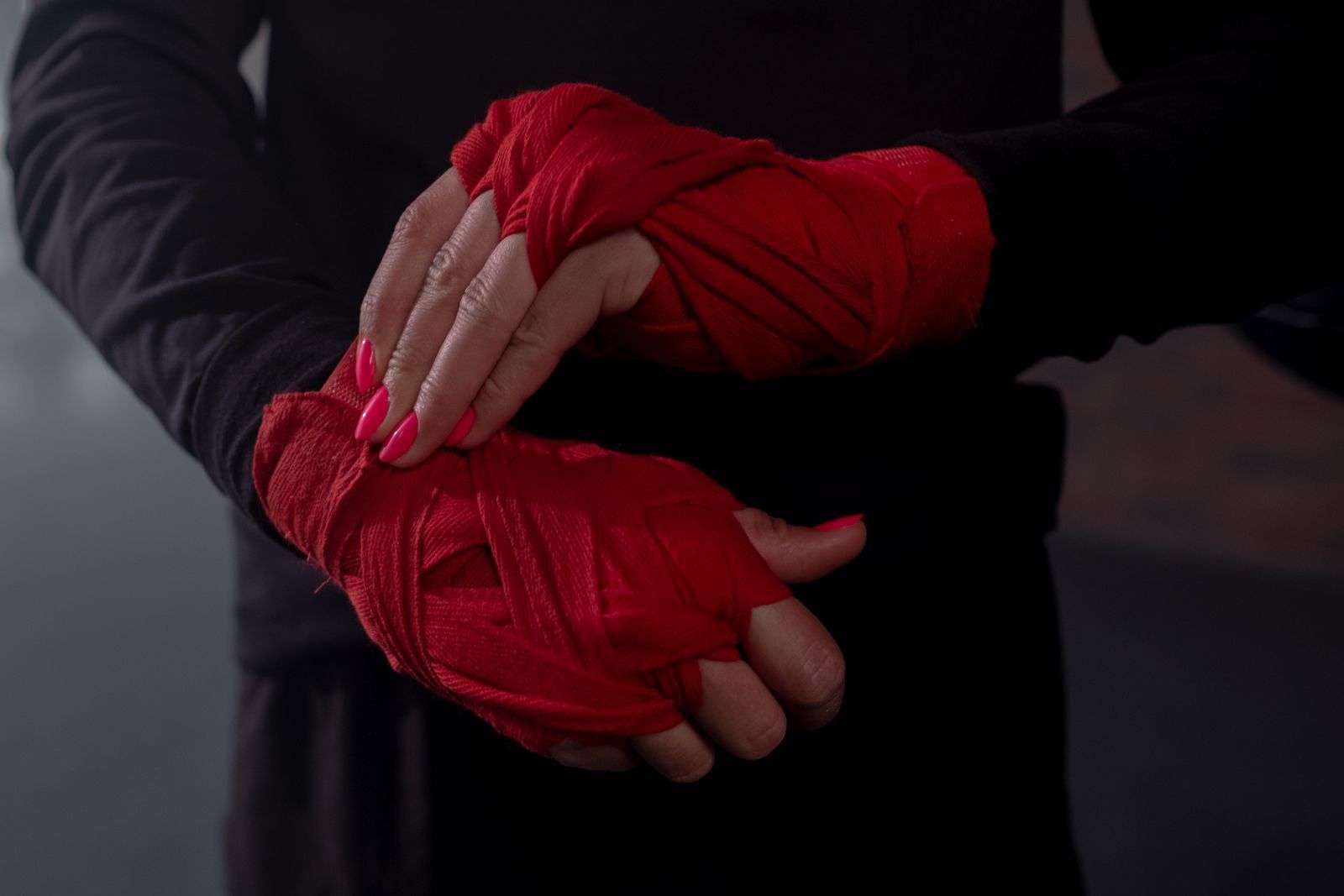 Close-up of hands wrapped in red hand wraps, one hand resting over the other