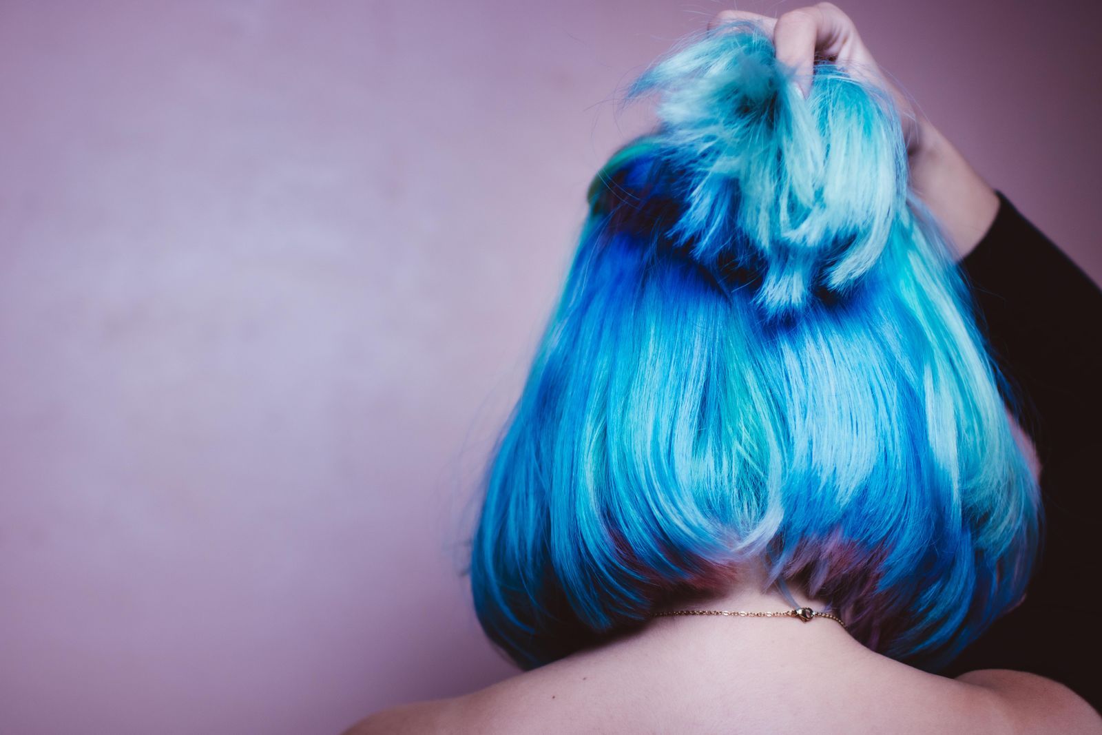 A blue bob with a messy top knot, seen from behind