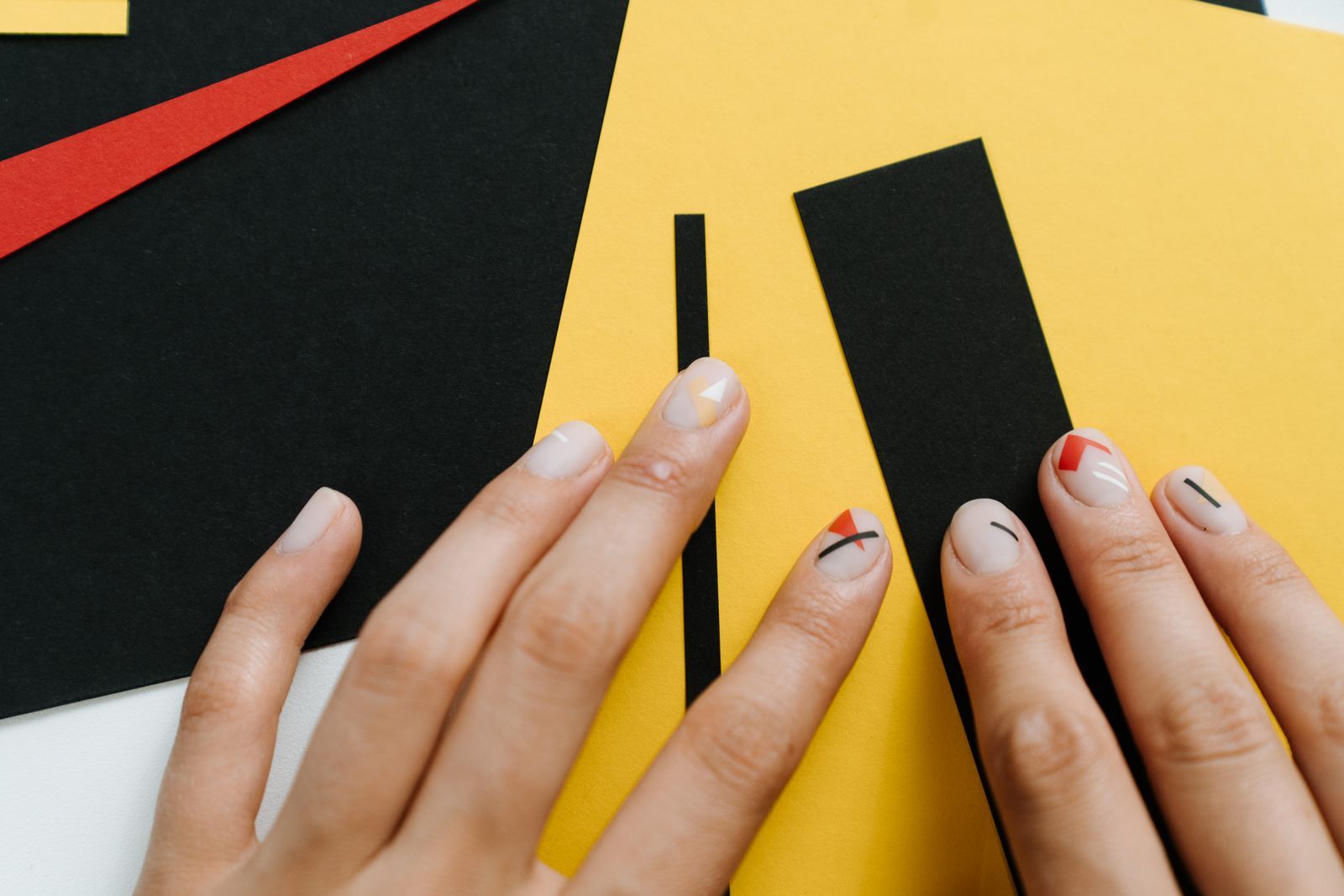 Bare nude nails with small black lines and red triangles