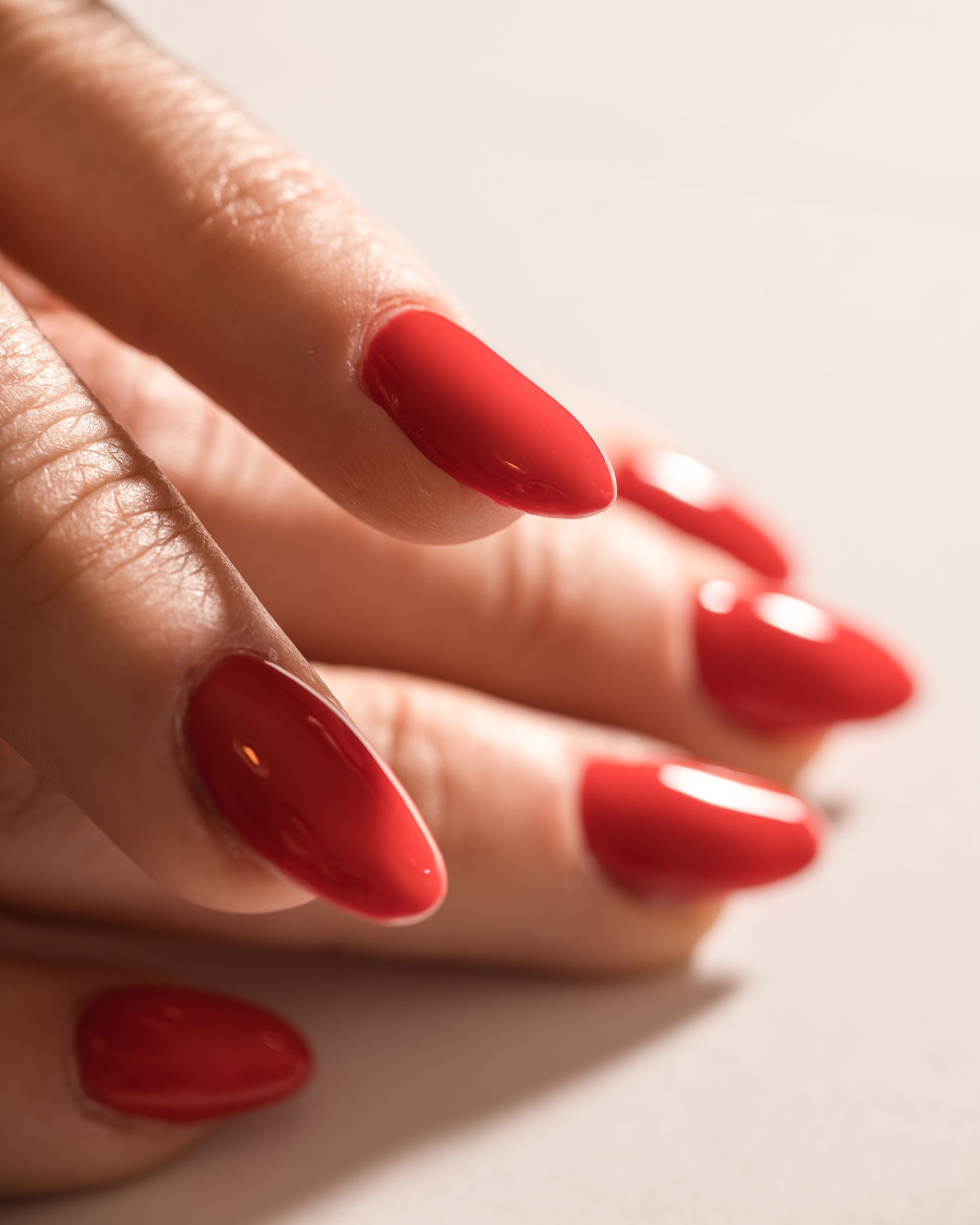 Close-up of glossy red almond-shaped gel nails