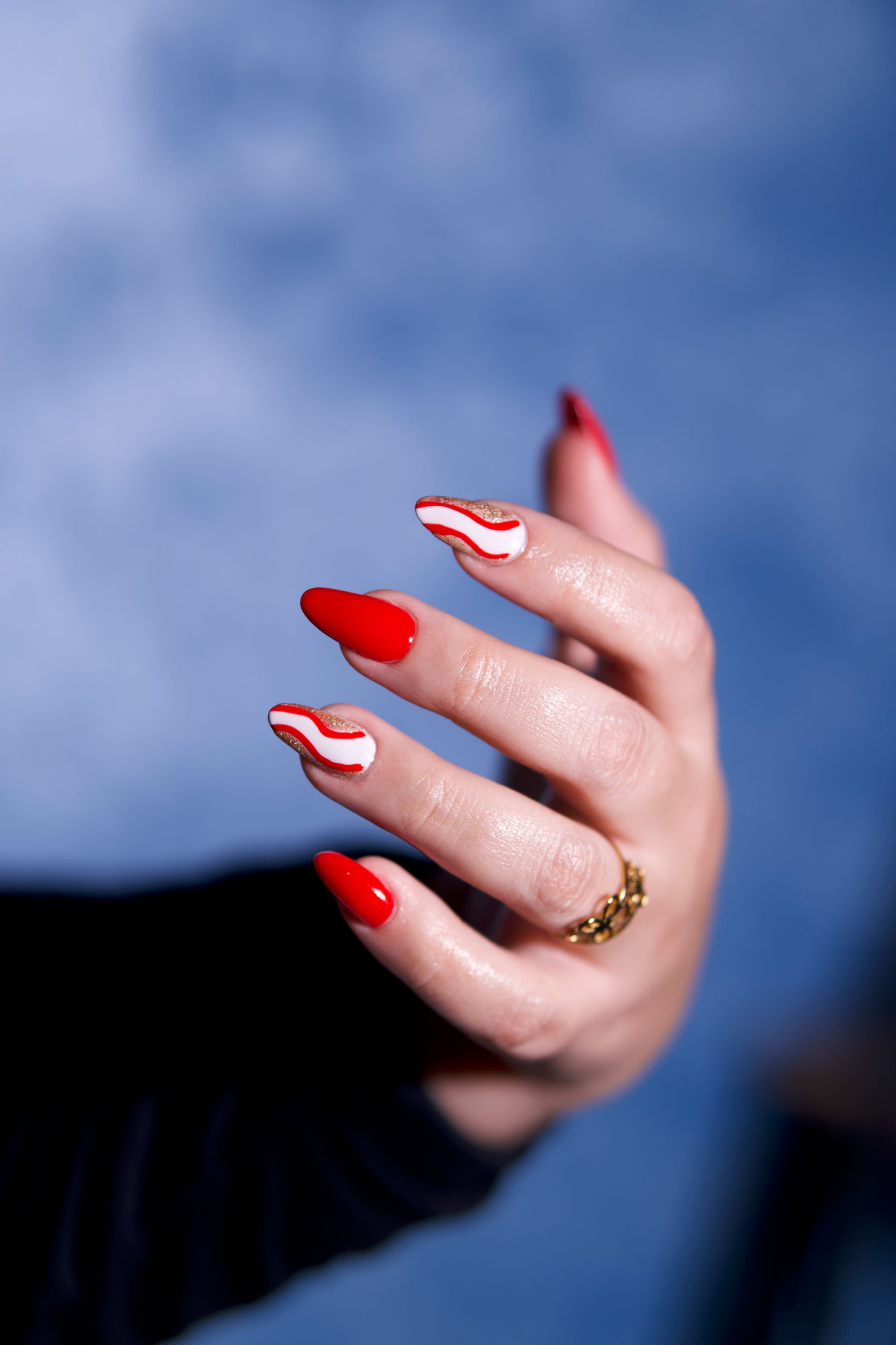 Red almond nails with a white hand-painted wave on two fingers