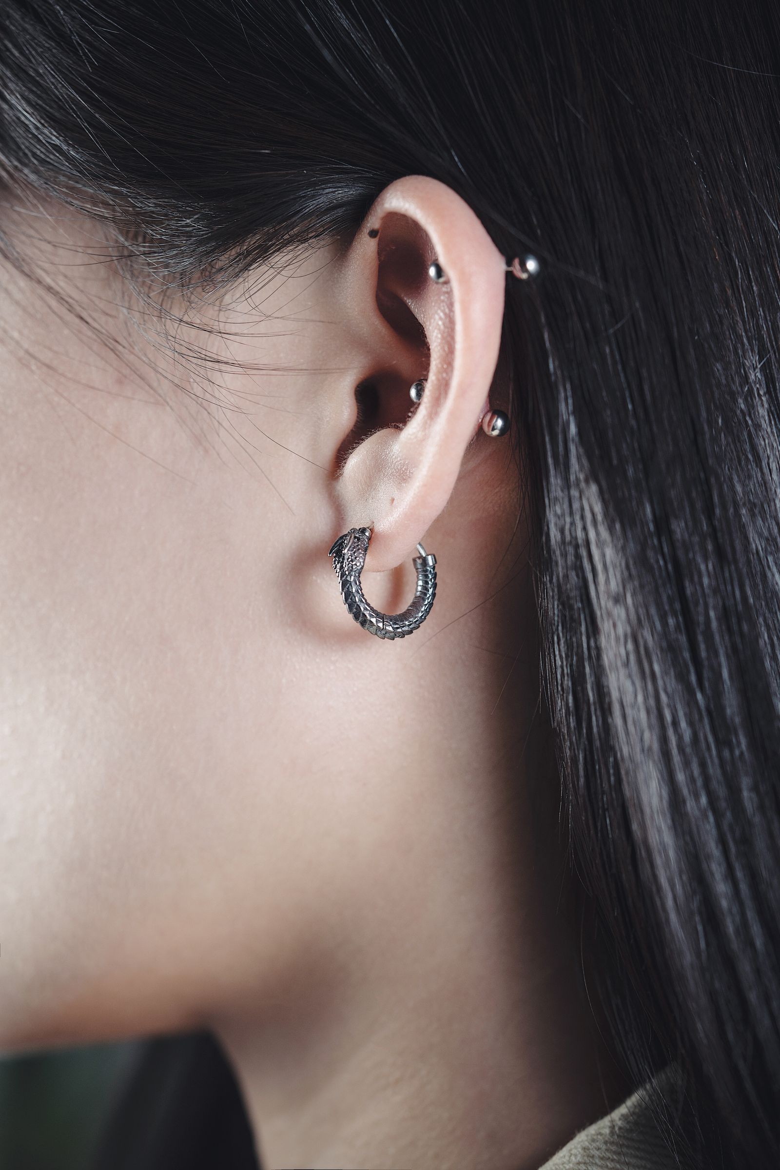 An ear with a curated stack of gold rings and studs