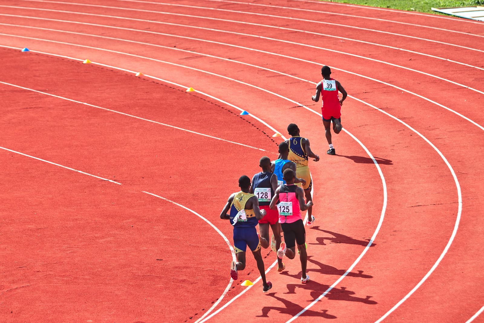 A pack of runners rounding the bend of a red track