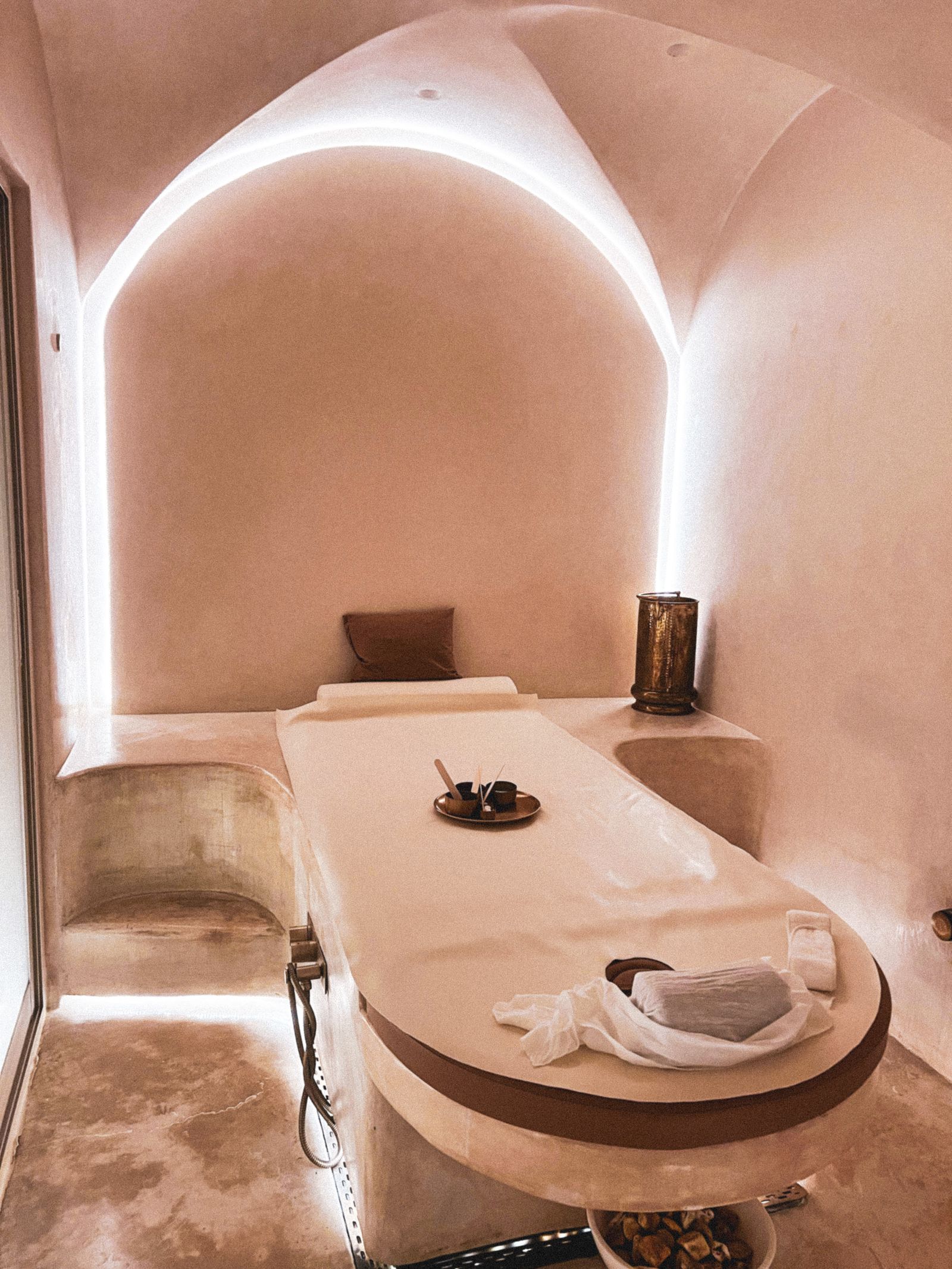 An arched treatment room with warm lighting and a padded treatment bed