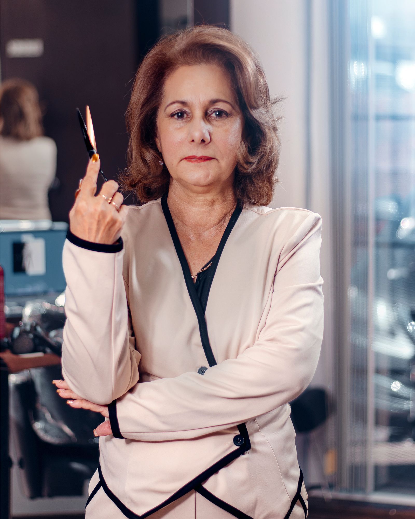 Diane Fontaine in a cream jacket, holding scissors upright