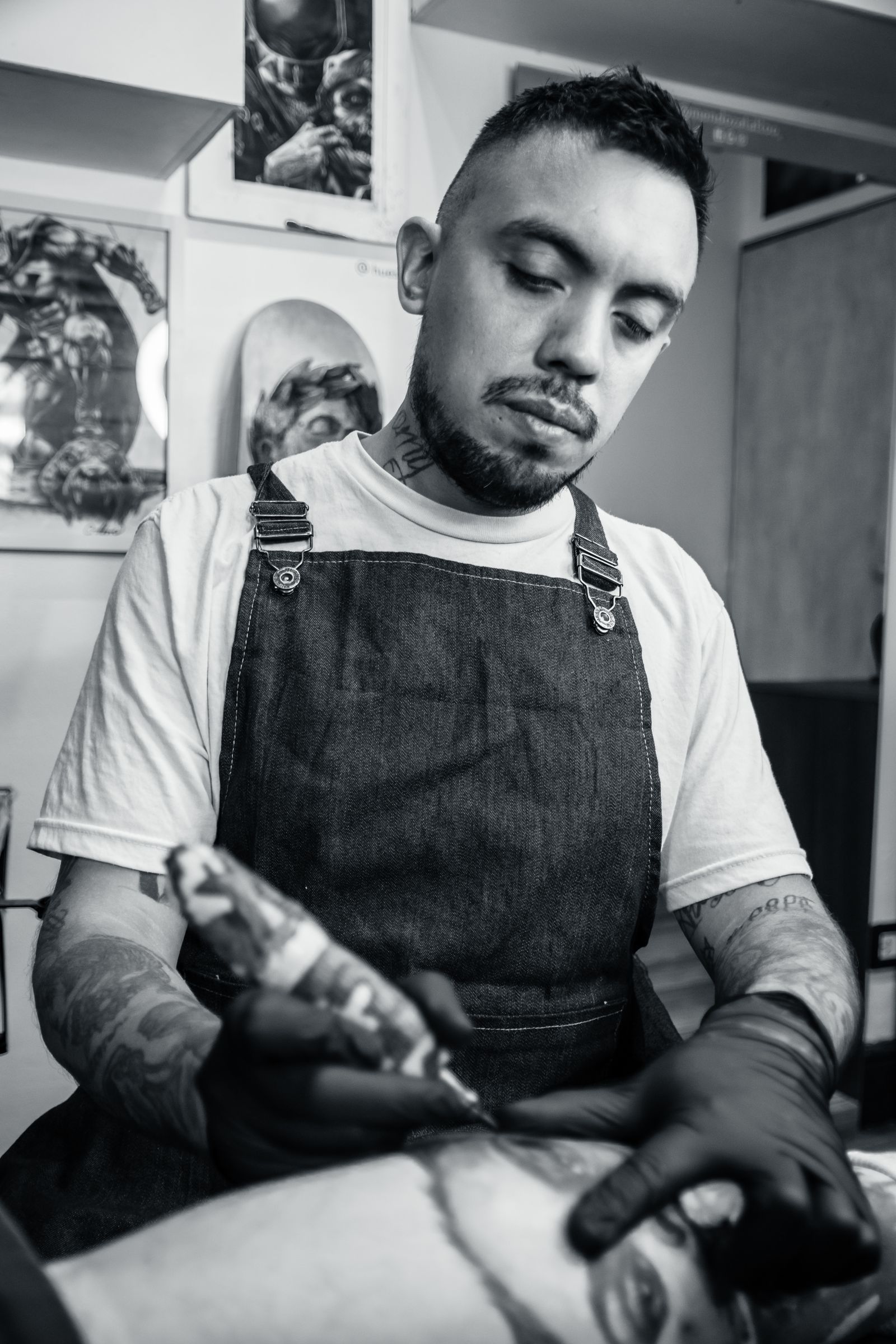 Ken Morimoto in a denim apron, tattooing