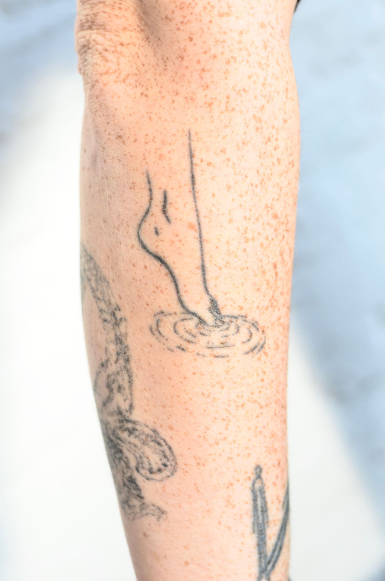 A single-line drawing of a foot dipping into water, on a forearm