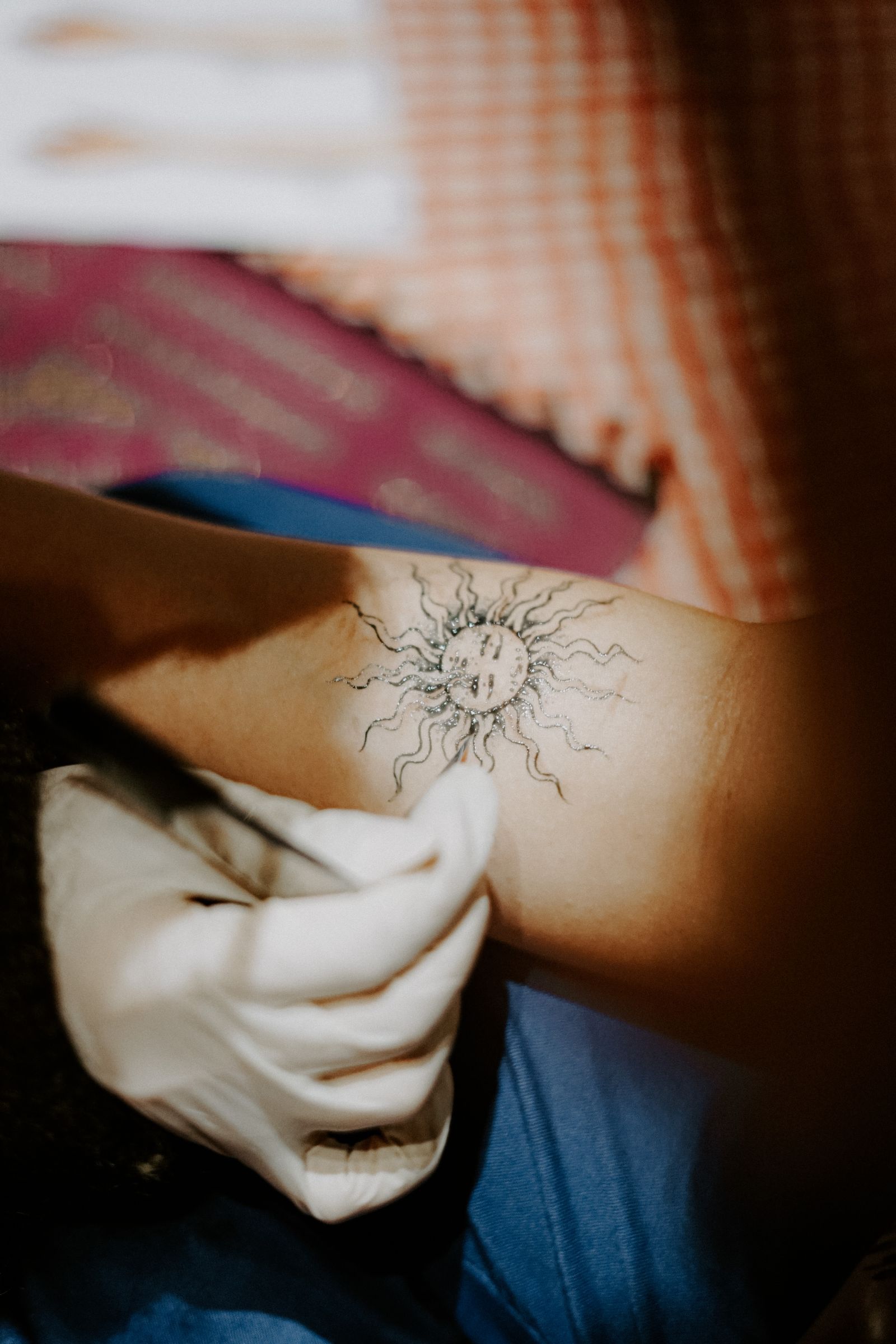 A fine-line sun with a face on an upper arm