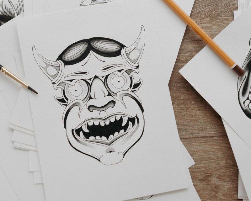 Black ink flash drawing of a horned mask with bared teeth